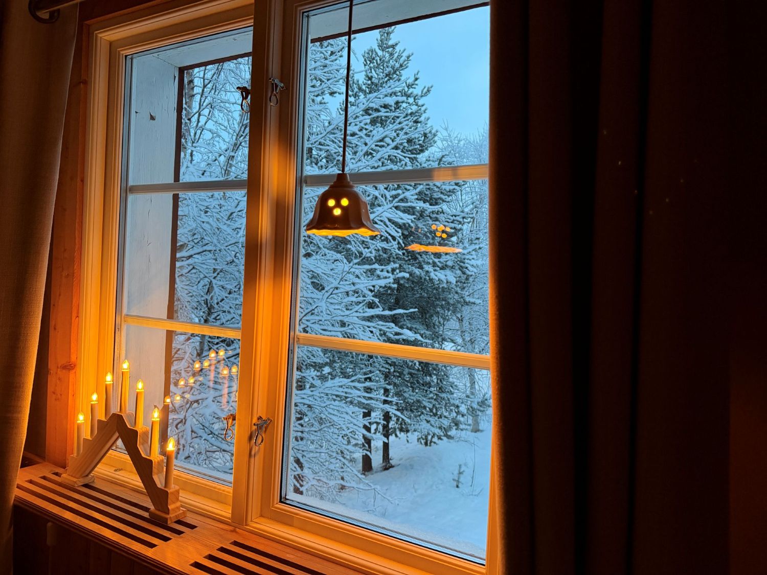 Cozy winter atmosphere inside Lappvall Lodge with candlelight and snowy forest view