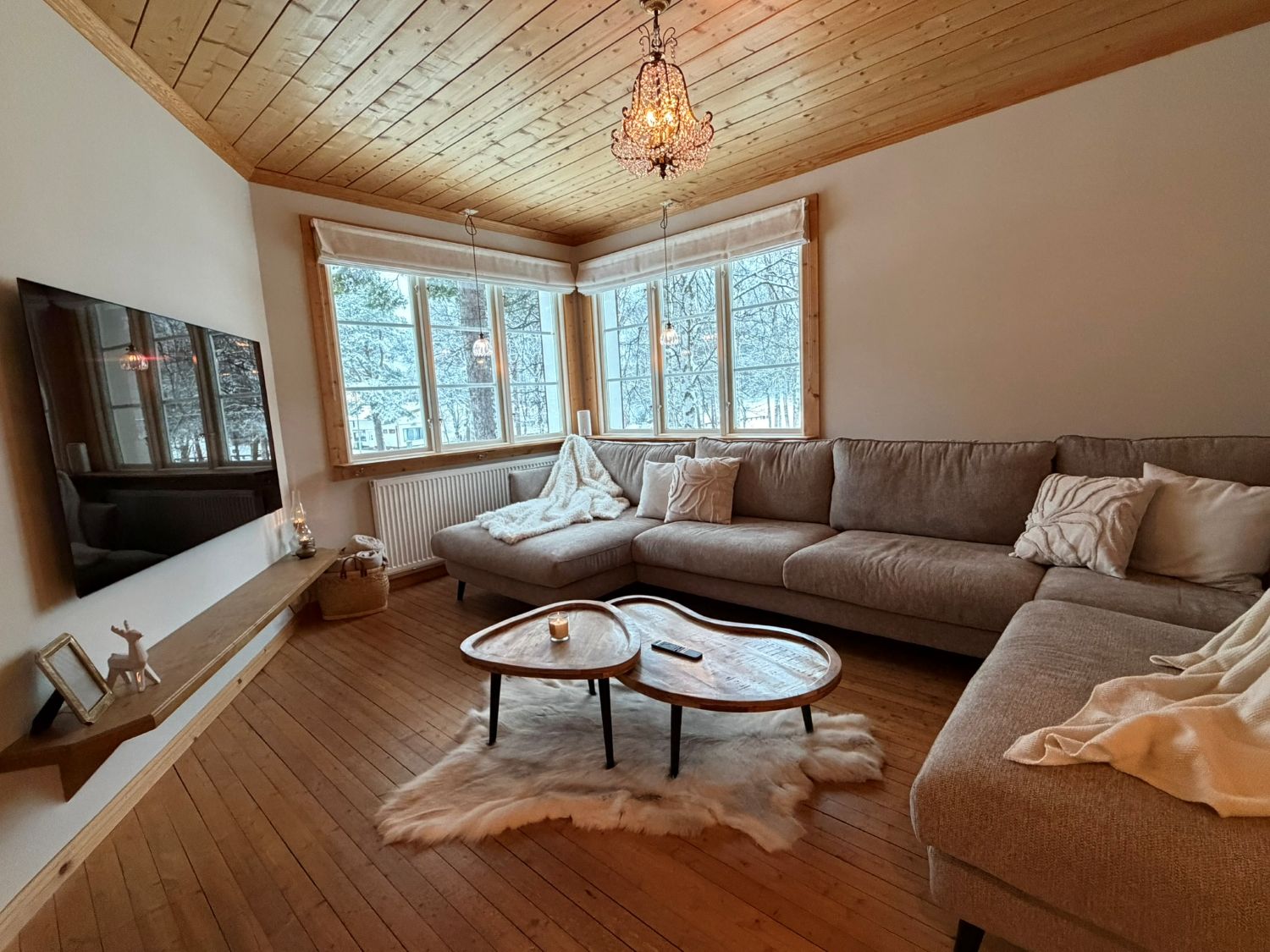 Living room at Lappvall Lodge in Arjeplog with wooden ceiling, large windows and winter views.