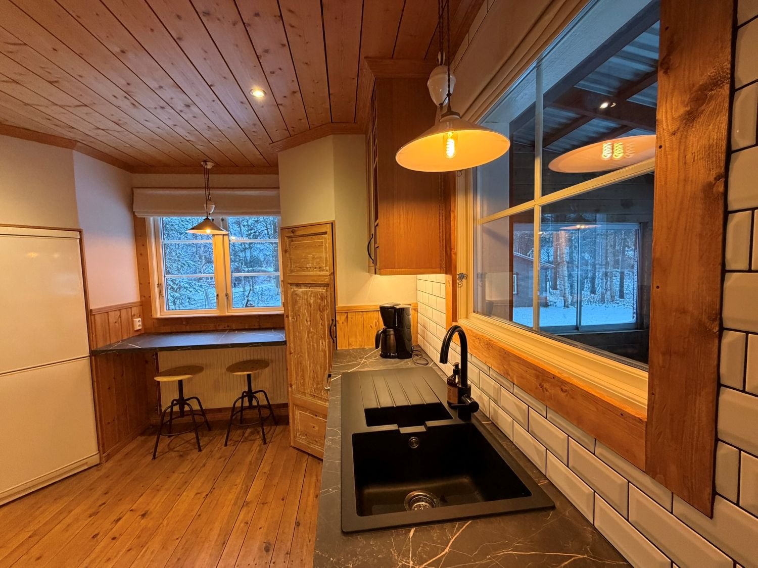 Kitchen sink with window view over snowy forest at Lappvall Lodge in Swedish Lapland
